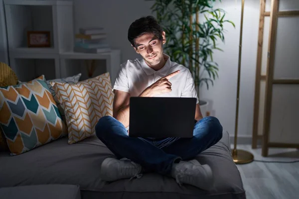Jovem Hispânico Usando Laptop Casa Noite Apontando Com Dedo Mão — Fotografia de Stock
