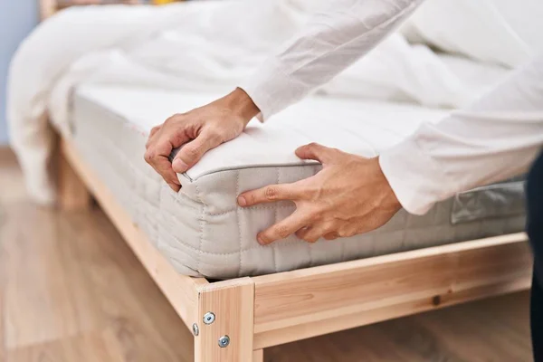 stock image Young hispanic man touching mattress at bedroom