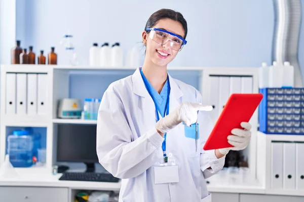 年轻美丽的惊慌失措的女科学家在实验室用触摸板带着自信地微笑 — 图库照片