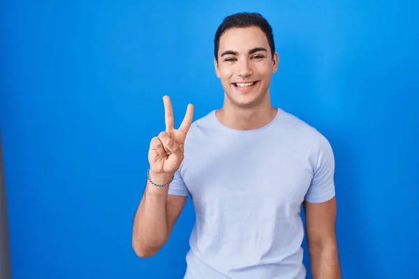 Joven Hombre Hispano Pie Sobre Fondo Azul Mostrando Señalando Hacia — Foto de Stock