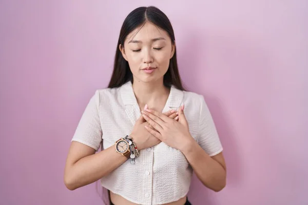 Chinese Young Woman Standing Pink Background Smiling Hands Chest Closed — Stockfoto