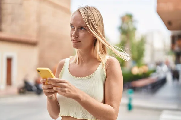 Νεαρή Ξανθιά Γυναίκα Που Χρησιμοποιεί Smartphone Χαλαρή Έκφραση Στο Δρόμο — Φωτογραφία Αρχείου