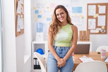 Genç, güzel, İspanyol bir iş kadını ofiste kendinden emin gülümsüyor.