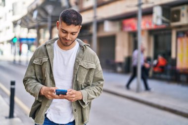 Sokakta akıllı telefon kullanan, kendine güvenen genç bir İspanyol.
