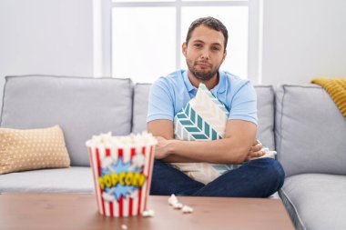 Hispanic man watching tv at home sitting on the sofa depressed and worry for distress, crying angry and afraid. sad expression. 