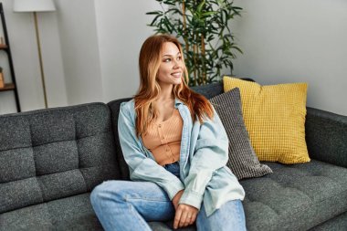 Kafkasyalı genç bir kadın evdeki kanepede kendinden emin bir şekilde oturuyor.