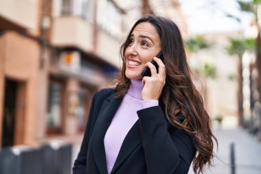 Genç İspanyol kadın gülümsüyor. Kendine güveniyor. Akıllı telefondan konuşuyor.