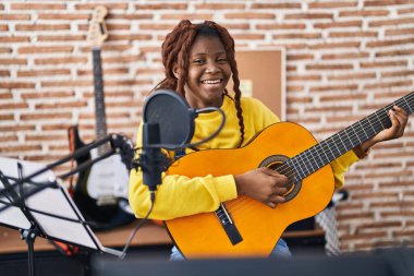 Afrikalı Amerikalı kadın müzisyen müzik stüdyosunda klasik gitar çalıyor.
