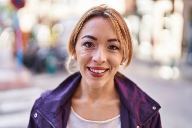 Sokakta kendinden emin gülümseyen genç bir kadın