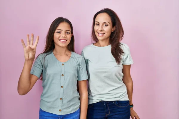 Pembe Arka Planda Duran Genç Anne Kız Parmaklarıyla Dört Numarayı — Stok fotoğraf