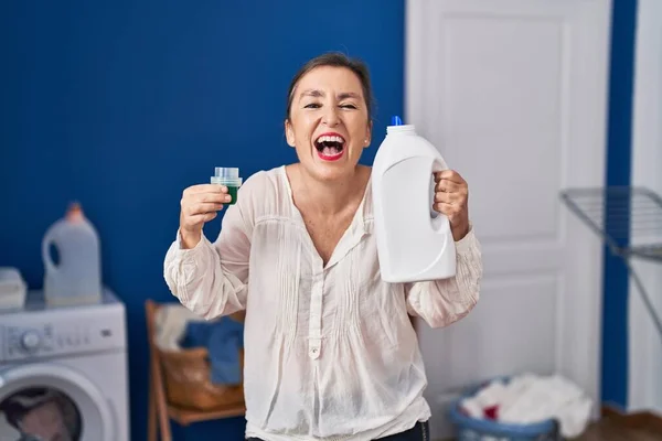 Middle Age Hispanic Woman Holding Detergent Bottle Smiling Laughing Hard — Stock Photo, Image