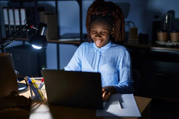 面白い表情で幸せ舌を突き出す夜オフィスで働くアフリカ人女性 感情の概念 — ストック写真