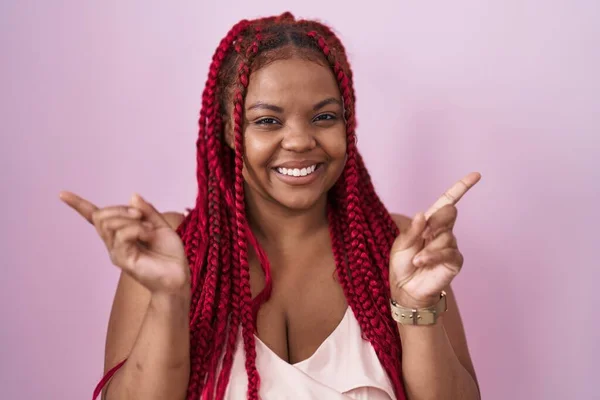 Африканская Американка Плетеными Волосами Стоящая Розовом Фоне Уверенно Улыбаясь Указывая — стоковое фото