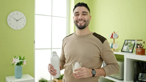 Young arab man smiling confident holding milk at home
