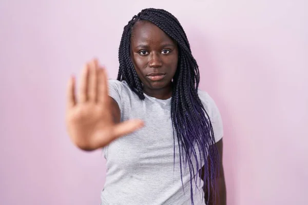 ピンクの背景に立っている若いアフリカの女性は 手の手のひらで歌うのをやめます 顔に負の重大なジェスチャーで — ストック写真