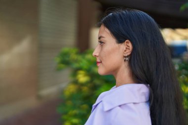 Young beautiful hispanic woman looking to the side with serious expression at street