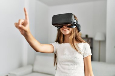 Evde video oyunu oynayan sevimli bir kız VR gözlük kullanıyor.