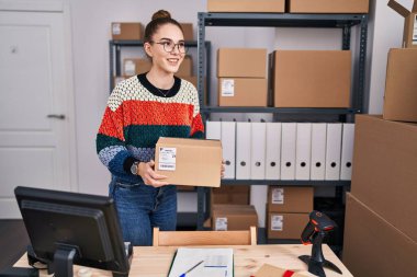 Young woman ecommerce business worker holding package at office