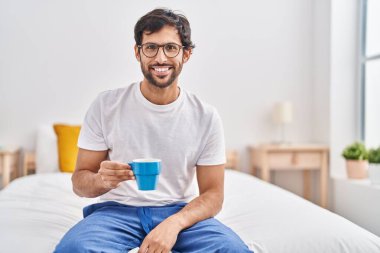 Genç İspanyol adam yatak odasında bir fincan kahve içiyor.