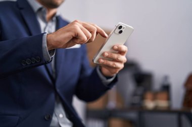 Young hispanic man business worker using smartphone at office