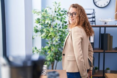 Genç, güzel, İspanyol bir iş kadını. Ofiste kendinden emin bir şekilde gülümsüyor.