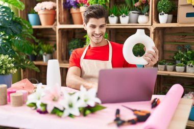 Çiçekçide dizüstü bilgisayar kullanan İspanyol bir çiçekçi.