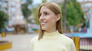 Young blonde woman smiling confident looking to the side at park