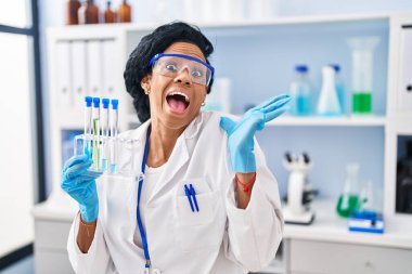 Orta yaşlı İspanyol kadın, bilim adamlarının laboratuarında mutlu bir gülümsemeyle zaferi kutluyor. 