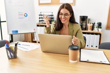 Genç ve güzel İspanyol iş kadını ofiste video görüşmesi yapıyor.