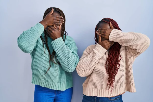 Две Африканки Стоящие Синем Фоне Закрывая Глаза Рот Руками Удивлены — стоковое фото