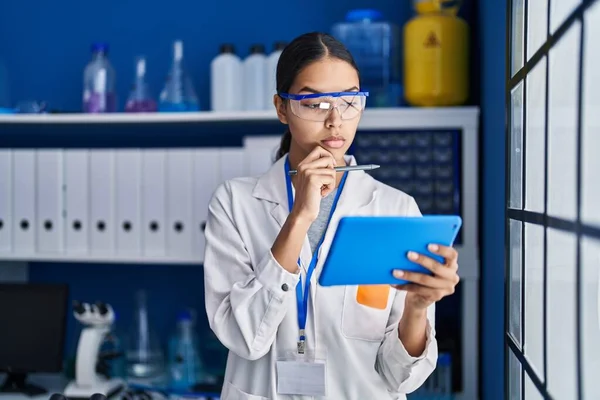 アフリカ系アメリカ人の若い女性科学者が実験室で疑わしい表現でタッチパッドを使う — ストック写真