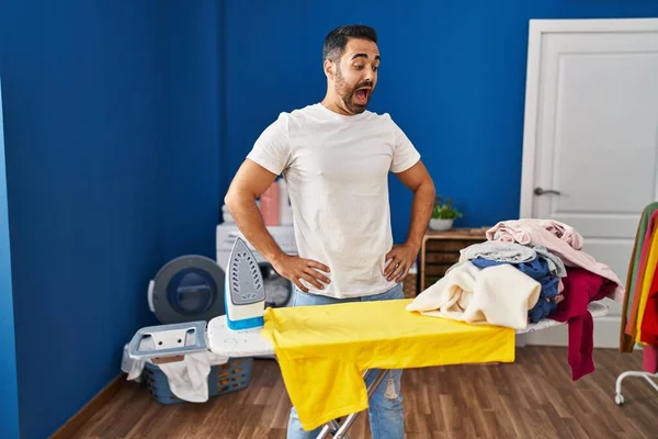 Ung Latinamerikansk Man Med Överraskande Uttryck Tittar Kläder Tvättstuga — Stockfoto