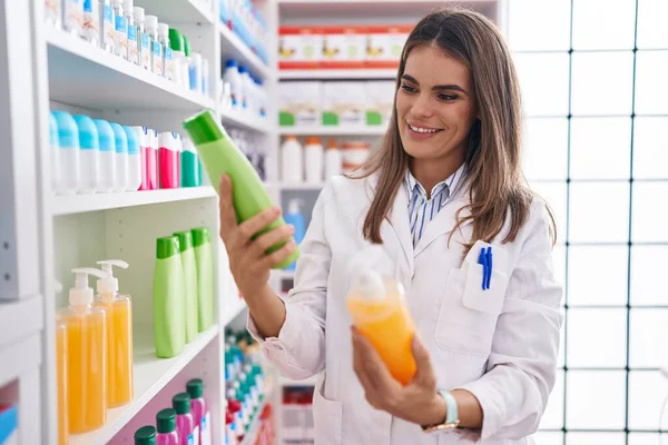 Young Beautiful Hispanic Woman Pharmacist Holding Shampoo Bottles Pharmacy — Fotografia de Stock