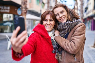 Two women mother and daughter make selfie by smartphone at street