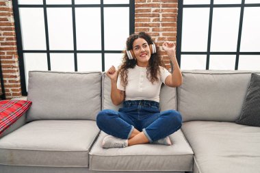 Genç, güzel İspanyol kadın evde müzik dinliyor ve dans ediyor.