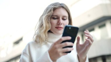 Sokakta duran akıllı telefonu kullanan genç sarışın kadın.