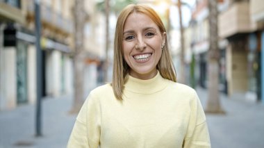 Sokakta kendine güvenen genç sarışın kadın gülümsüyor