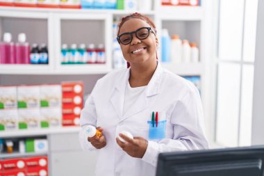 African american woman pharmacist holding pills bottles at pharmacy