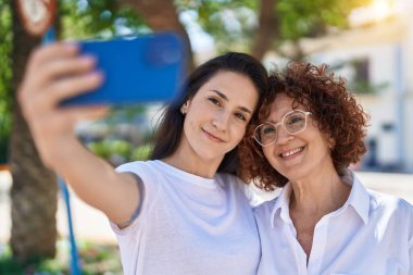 İki kadın anne ve kız parkta akıllı telefondan selfie çekiyorlar.
