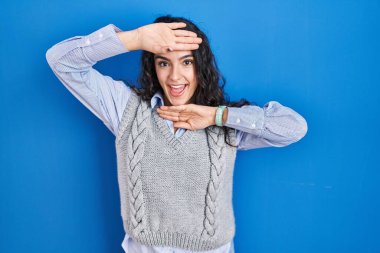 Mavi arka planda duran esmer, neşeli gülümseyen ve elleri yüzünü gösteren genç bir kadın. Şaşırdım ve çıktım. 