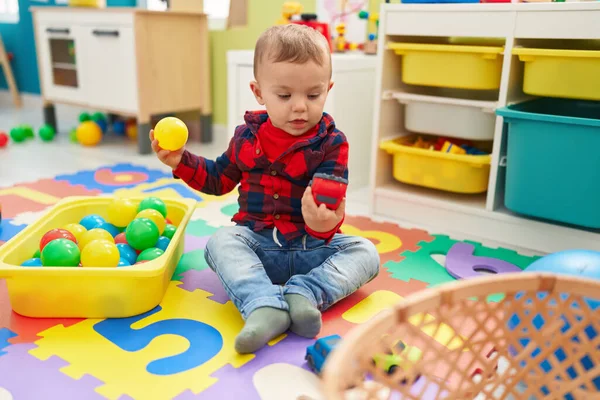 愛らしいブロンド幼児遊びとともにボールと車のおもちゃ座っています床に幼稚園 — ストック写真