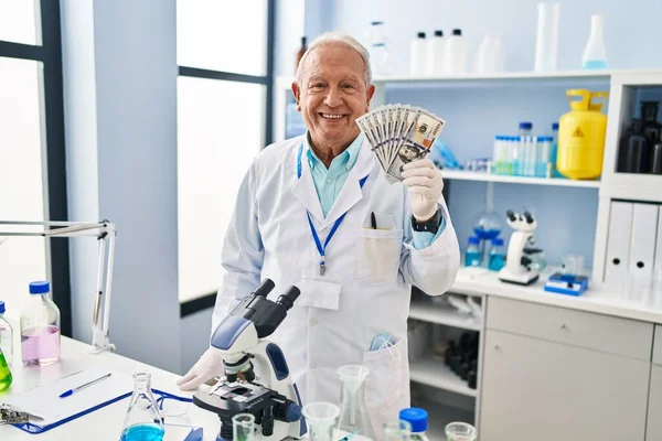 研究室で働いている灰色の髪を持つ上級科学者は 肯定的で幸せな立場を見て 歯を示す自信を持って笑顔で笑っています — ストック写真