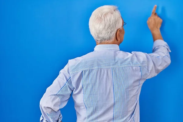 Hispanic Senior Man Wearing Glasses Posing Backwards Pointing Ahead Finger — Stock Photo, Image