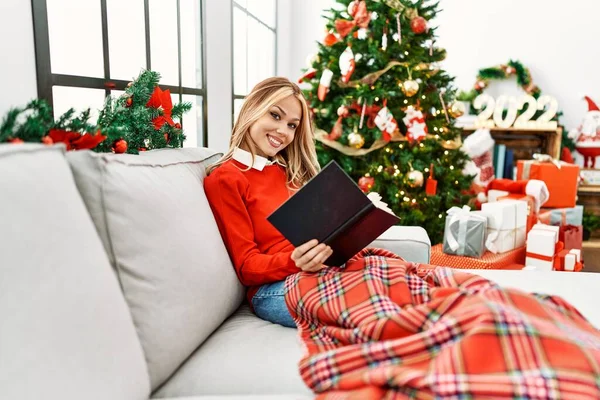 Νεαρή Καυκάσια Γυναίκα Διαβάζει Βιβλίο Κάθεται Στον Καναπέ Από Χριστουγεννιάτικο — Φωτογραφία Αρχείου