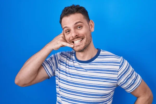 Young Hispanic Man Standing Blue Background Smiling Doing Phone Gesture — Zdjęcie stockowe