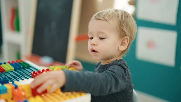 Anaokulundaki Masada Oturan Sevimli Sarışın Çocuk Inşaat Bloklarıyla Oynuyor — Stok fotoğraf