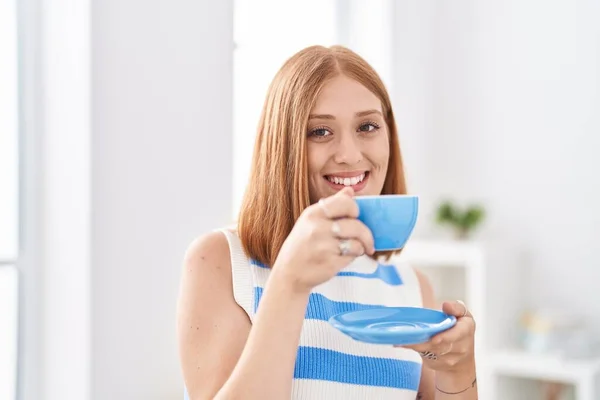 Młoda Ruda Kobieta Uśmiecha Się Pewnie Pijąc Kawę Domu — Zdjęcie stockowe