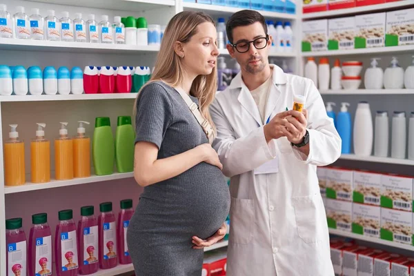 男男女女药剂师和孕妇病人拿着药瓶在药店讲话 — 图库照片