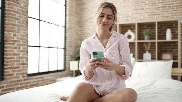 Νεαρή Ξανθιά Γυναίκα Που Χρησιμοποιεί Smartphone Κάθεται Στο Κρεβάτι Στο — Φωτογραφία Αρχείου