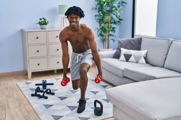 stock image African american man training legs exercise using dumbbells at home